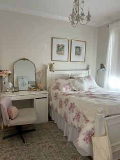 a white bed sitting next to a window in a bedroom under a chandelier