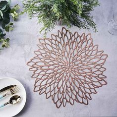 a white plate and silverware are sitting on a table with green plants in the background