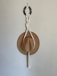 a hat hanging on the wall with a pair of scissors attached to it's side