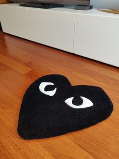 a black heart shaped rug with eyes on the floor in front of a flat screen tv