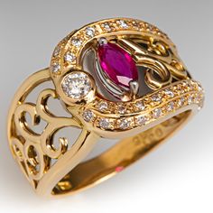 This fantastic 18K yellow gold ring features a pierced design filled with scroll details that are backed with curved platinum backgrounds. The ring is accented with one (1) prong set marquise cut natural ruby, one (1) bezel set round brilliant cut diamond, and forty-six (46) bead set round brilliant cut diamonds. The ring measures 12.3mm at the top, rises 4.4mm above the finger, tapering to 2.9mm wide and 0.8mm thick at the base of the shank. "0.31 D038 Pt900 18K is stamped on the inside shank. It is currently a size 5.75. Luxury Marquise Ruby Ring, Luxury Ruby Marquise Cut Ring For Formal Occasions, Luxury Ruby Ring Marquise Cut For Formal Events, Luxury Marquise Cut Ruby Ring For Formal Occasions, Elegant Marquise Ruby Ring With Diamond Cut, Gold Marquise Ruby Ring With Diamonds, Luxury Marquise Cut Yellow Gold Ruby Ring, Luxury Marquise Ruby Ring For Wedding, Luxury Marquise Cut Ruby Ring In Yellow Gold