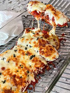 two pieces of pizza on a wire rack with cheese and sauce being lifted from it