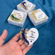 three boxes with wedding favors in them on a blue cloth covered tablecloth, one is holding a heart shaped box and the other two are filled with confetties