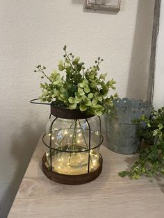 a potted plant sitting on top of a wooden table next to a metal container filled with greenery