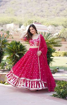 a woman in a red and white lehenga is posing for the camera with her hand on her hip