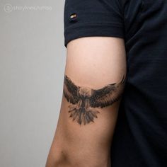 a man's arm with an eagle tattoo on the left side of his arm