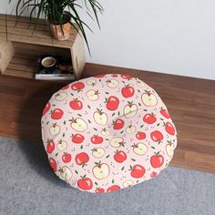 an apple print round poufce on the floor next to a potted plant