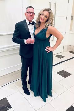 a man in a tuxedo and woman in a gown posing for the camera