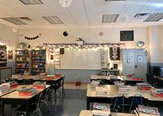 an empty classroom with desks and books on the walls, lights strung from overhead