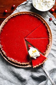 a piece of pie on a plate with whipped cream and cranberry sauce in the background