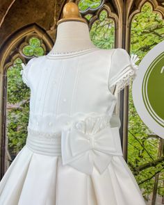 An adorable first communion gown made with off-white rustic organza with laces and pleats. It has covered buttons on the back for closure. Made in Spain Dry Clean 100% polyester Final sale, no exchanges nor returns are available Fitted Dress With Bow For Confirmation, First Communion Dress With Ruffles And Fitted Bodice, Fitted First Communion Dress With Ruffles, Fitted First Communion Dress With Ruffles For Ceremony, Fitted Ruffled First Communion Dress, White Bow Dress For First Communion And Baptism, White Confirmation Dress With Satin Bow, Fitted Dresses With Satin Bow For First Communion, First Communion Dress