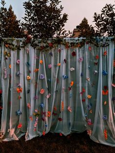 the curtain is covered with flowers and leaves on it's side, next to some trees