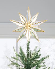 a christmas tree topper hanging from the ceiling in front of a window with snowflakes on it