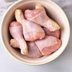 raw chicken pieces in a bowl next to a jar of mayonnaise on a marble countertop