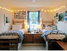 two twin beds in a bedroom with string lights on the wall and pictures above them