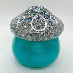 a small blue vase with glitter on it's top and a white circle in the middle