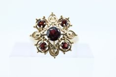 Beautiful Garnet Flower Cluster ring. Open Work starburst effect. 10k Yellow Gold Estate ring. Details: 3.1grams total weight 5mm center and 3mm wide surrounding garnets. 5 Total 17mm wide top size 6.5 Flower Cluster Ring, Starburst Ring, Star Cluster, Flower Cluster, Estate Rings, Cluster Ring, Garnet, Jewelry Rings, Yellow Gold