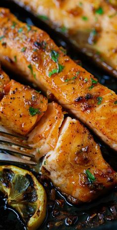 grilled salmon and lemons in a skillet with a fork on the side