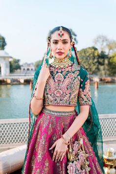 The bridal Lehenga Choli and Dupatta Dress for Wedding has an alluring blend of pink and green shades and it wins everyone's hearts at the very first glance with its charm and elegance. Lavish embroidery and embellishments make this Lehenga Dress an epitome of beauty. Bridal Choli: The choli in premium raw silk is fully emblazoned with lavish designs and fine details of embroidery. Goldwork and perfect stitching make this choli in an alluring green shade a perfect choice to pair with the Lehenga Pink Sets With Intricate Embroidery For Traditional Ceremonies, Green Embroidered Lehenga For Wedding, Green Lehenga With Intricate Embroidery For Wedding, Green Wedding Sets With Intricate Embroidery, Green Lehenga With Pallu For Wedding, Green Choli With Intricate Embroidery For Wedding, Wedding Green Choli With Intricate Embroidery, Wedding Green Embroidered Sharara, Green Wedding Choli With Intricate Embroidery