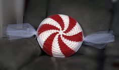 a red and white knitted peppermint candy pillow sitting on top of a chair