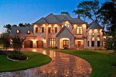 a large brick house with lots of windows and lights on it's front entrance