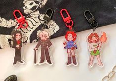 four keychains with cartoon characters on them sitting next to a pair of scissors