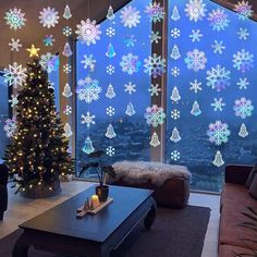 a living room decorated for christmas with snowflakes hanging from the windows and a lit tree