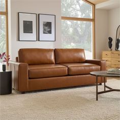 a brown leather couch sitting in front of a window