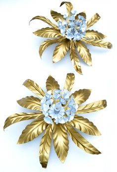 two gold and blue flower brooches on a white background