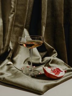 a glass of wine sitting on top of a table next to a pomegranate