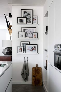 a kitchen with white cabinets and pictures on the wall