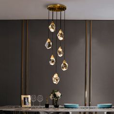 a dining room table with plates and glasses hanging from the chandelier above it