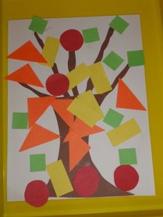 an art project made with construction paper and colored stickers on a yellow frame, depicting a tree