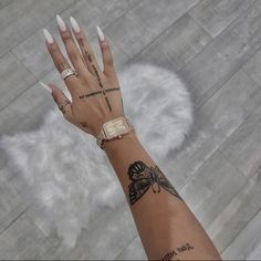 a woman's hand with tattoos and rings on her left wrist, next to a white rug