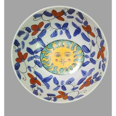 a decorative bowl with an image of the sun on it's face in blue, red and yellow