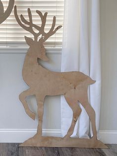 a wooden deer standing next to a window