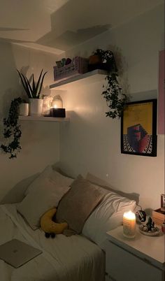 a bed with white sheets and pillows next to a shelf filled with plants on top of it