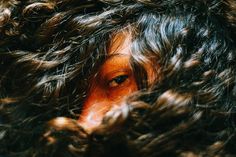 a close up view of a woman's face with long, curly hair on her head