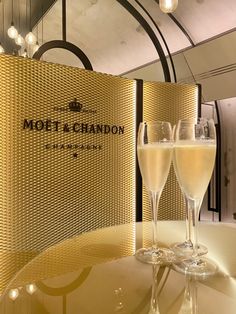 two champagne glasses sitting on top of a table next to a sign that says mott and chanon