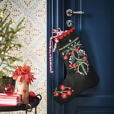 a christmas stocking hanging on a door handle next to a small tree and presents