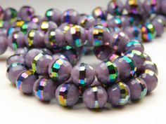 purple beads with iridescent colors are arranged on a white surface