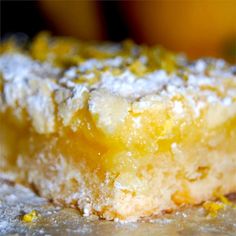 a close up of a piece of cake with powdered sugar and lemons in the background