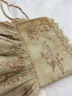 an old piece of cloth with birds and flowers on it sitting on a white surface