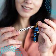 a woman is holding a keychain with the word maybe written on it in small letters