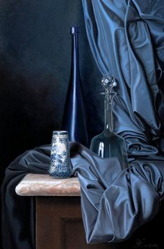 a blue vase sitting on top of a wooden table next to a black cloth covered wall