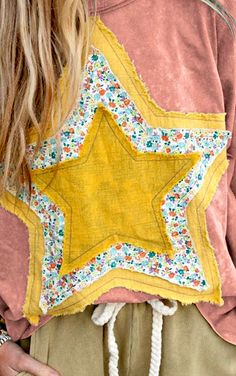 a woman wearing a pink shirt with a yellow star on the front and white string around her waist