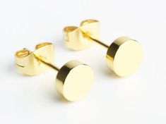 two pairs of gold toned earrings with round posts on the back and top, set against a white background