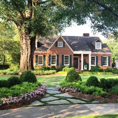 a brick house with green shutters and landscaping