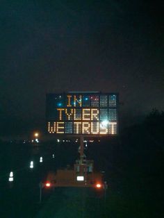 a large sign that is on the side of a building in the dark with lights