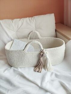 a white wicker basket sitting on top of a bed next to pillows and a pillow